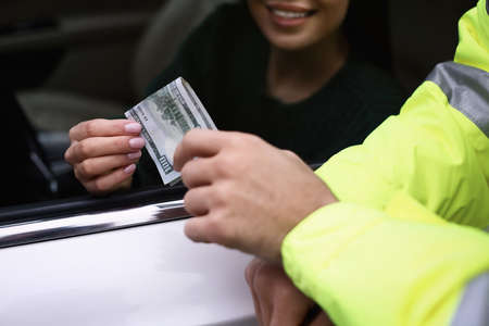 Woman giving bribe to police officer out of car window, closeupの写真素材