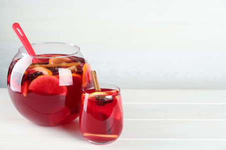 Glass and bowl of delicious aromatic punch drink on white wooden table. Space for textの写真素材