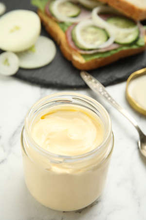 Jar of delicious mayonnaise near fresh sandwich on white marble tableの写真素材