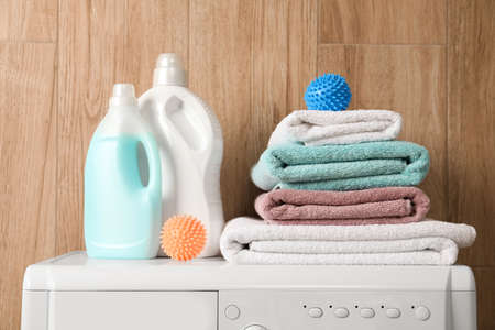 Dryer balls, stacked clean towels and detergents on washing machineの写真素材