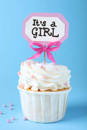 Beautifully decorated baby shower cupcake for girl with cream and topper on light blue backgroundの写真素材
