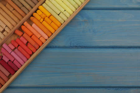 Drawing pastel set in box on light blue wooden background, top view. Space for textの写真素材