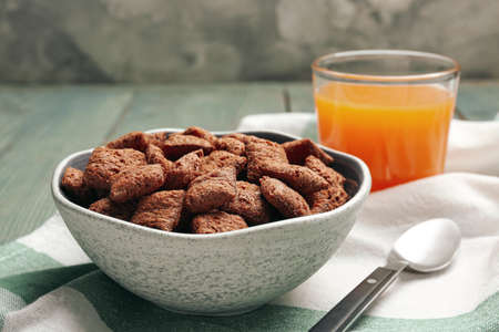 Bowl of sweet crispy corn pads and juice on blue wooden table. breakfast cereal