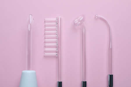 Modern darsonval with different nozzles on pink background, flat lay. Microcurrent therapyの写真素材