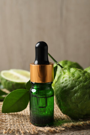 Bottle of essential oil and fresh bergamot fruits on tableの写真素材