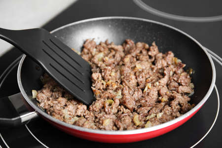 Frying minced meat in pan on induction stove, closeupの写真素材