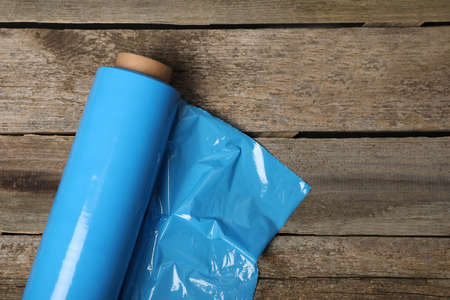 Roll of plastic stretch wrap film on wooden table, top view. Space for textの写真素材