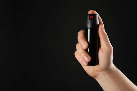 Man holding pepper spray on black background, closeup. Space for textの写真素材