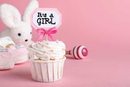 Beautifully decorated baby shower cupcake with cream and girl topper on pink background. Space for textの写真素材