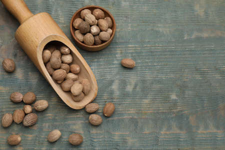 Bowl and scoop with nutmeg seeds on light blue wooden table, flat lay. Space for textの写真素材