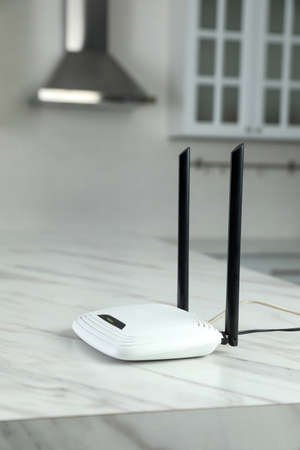 Modern WiFi router on white marble table in kitchen