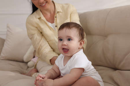 Mother with her cute baby on sofa at home, closeup