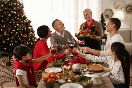 Happy family clinking glasses of drinks at festive dinner indoors. christmas celebration