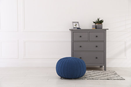 Stylish room interior with gray chest of drawers and blue pouf, space for textの写真素材
