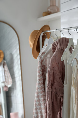 Rack with different stylish clothes and hat near mirror in dressing roomの写真素材