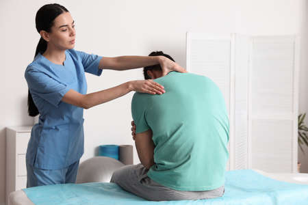 Orthopedist examining man's neck in clinic. scoliosis treatmentの写真素材