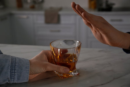 Man refusing to drink whiskey at home, closeup. Alcohol treatment addiction