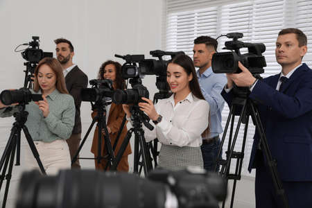 Group of journalists with cameras waiting for official person indoorsの写真素材