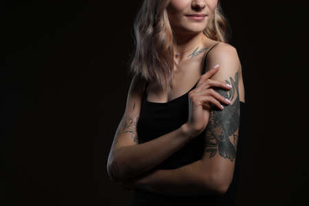 Beautiful woman with tattoos on body against black background, closeup. Space for textの写真素材