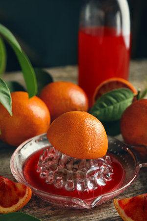 Squeezer with half of sicilian orange on wooden tableの写真素材