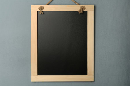 Clean small black chalkboard hanging on gray wallの写真素材