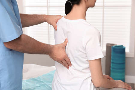 Orthopedist examining woman's back in clinic, closeup. scoliosis treatmentの写真素材