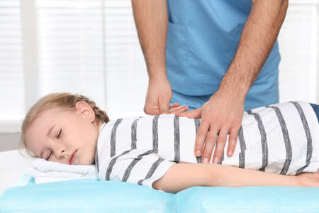 Orthopedist massaging child's back in clinic, closeup. scoliosis treatmentの写真素材