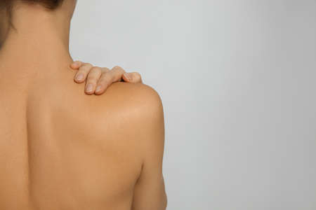 Back view of woman with perfect smooth skin on light gray background, space for text. beauty and body careの写真素材