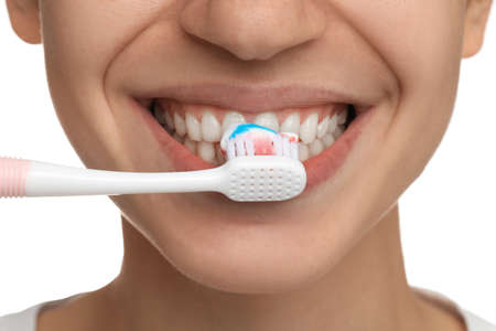 Woman brushing teeth with paste on white background, closeup. dental care
