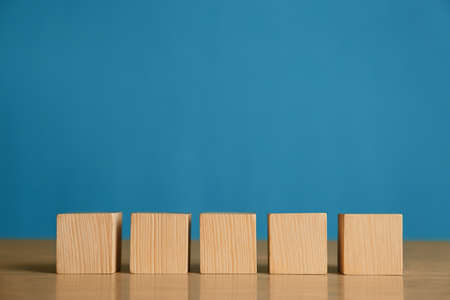 Row of blank cubes on wooden table against light blue background. Space for textの写真素材