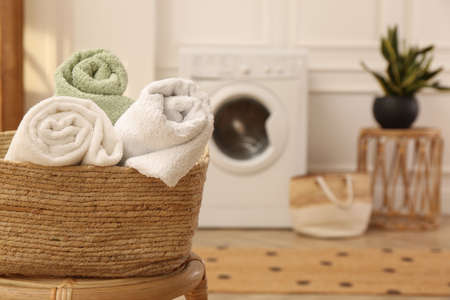 Basket with clean rolled towels on stool in laundry room. Space for textの写真素材