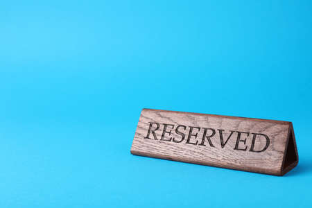 Elegant wooden sign Reserved on light blue background, space for textの写真素材