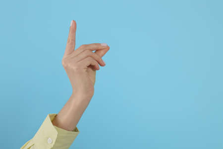 Woman snapping fingers on light blue background, closeup of hand. Space for textの写真素材