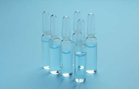 Many medical ampoules with solution for injection on light blue backgroundの写真素材