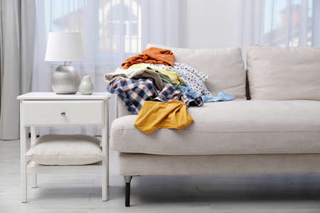 Messy pile of dirty clothes on sofa in living room. Tidying up method