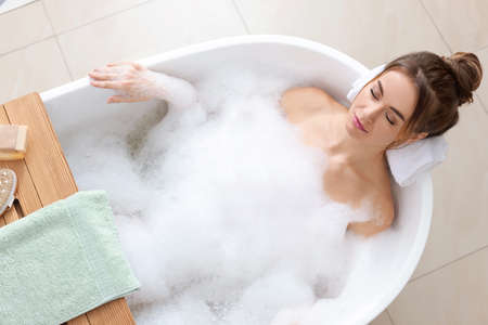 Beautiful woman enjoying bubble bath at home, above view