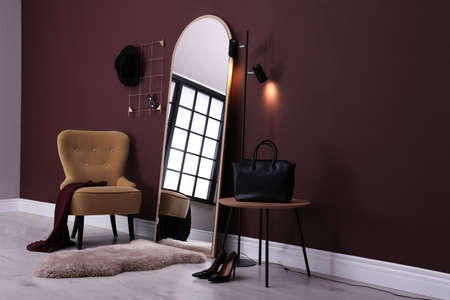 Elegant room interior with large mirror and comfortable armchair