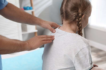 Orthopedist examining child's back in clinic, closeup. scoliosis treatmentの写真素材