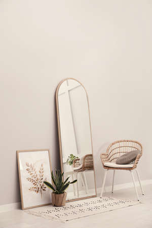 Beautiful mirror, armchair and plant near white wall indoors. interior designの写真素材