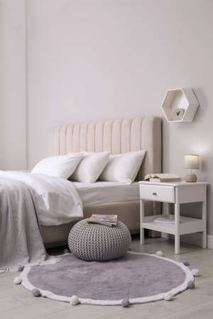 Stylish bedroom interior with knitted pouf and furnitureの写真素材