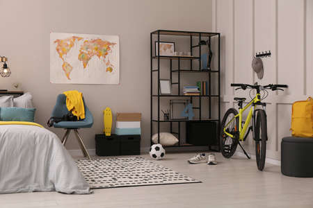 Stylish teenager's room interior with comfortable bed and sports equipment