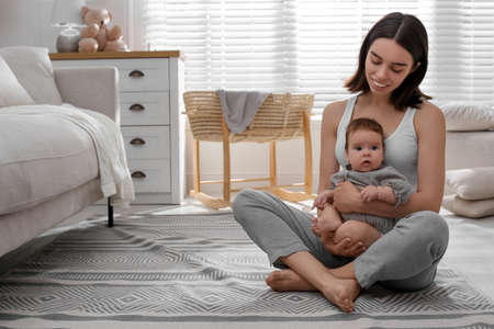 Young woman with her little baby on floor at home