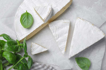 Delicious brie cheese with basil on light gray table, flat layの写真素材