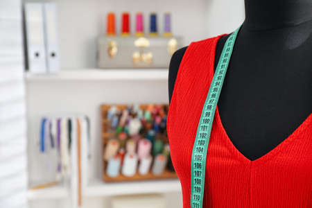 Mannequin with dress and measuring tape in tailor studio. Space for textの写真素材