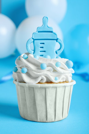 Beautifully decorated baby shower cupcake for boy with cream and topper on light blue backgroundの写真素材