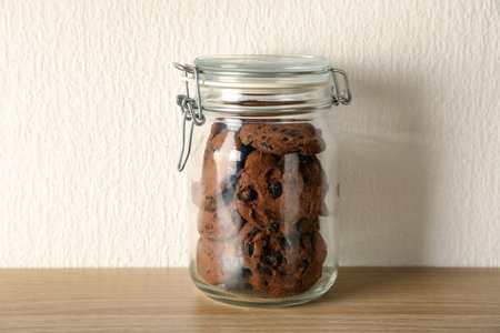 Delicious chocolate chip cookies in glass jar on wooden tableの写真素材