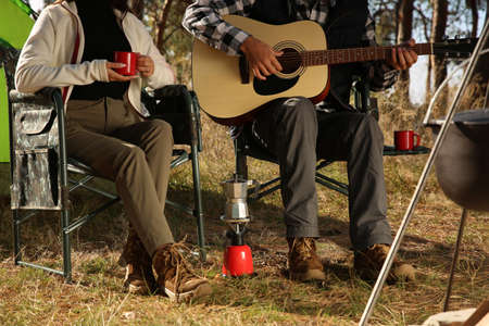 Couple with guitar resting in camping chairs outdoors, closeupの写真素材