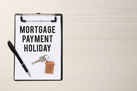 Clipboard with words Mortgage Payment Holiday, key and pen on white wooden table, top view. Space for textの写真素材