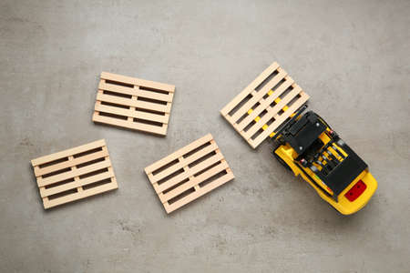 Toy forklift and wooden pallets on light gray table, flat layの写真素材