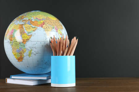 Globe, books and school supplies on wooden table near black chalkboard, space for text. Geography lessonの写真素材